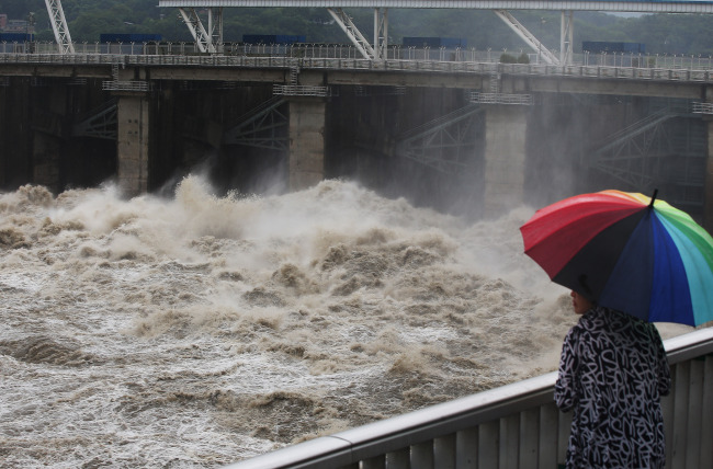 A citizen watches Paldang Dam dumping around 3,409 tons of water per second after being hit by torrential rain in Hanam, Gyeonggi Province, Tuesday. (Yonhap)