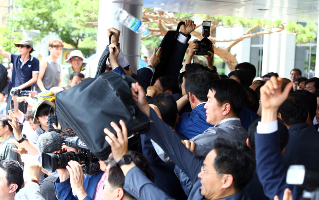 Security guards and officials block using their carry-ones and umbrellas as residents throw eggs and water bottles at visiting Prime Minister Hwang Kyo-ahn over the THAAD deployment in front of the Seongju county office in North Gyeongsang Province on Friday. (Yonhap)