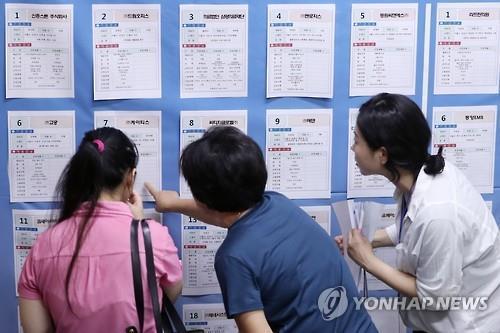 People browse through recruitment advertisements at a job fair in Seoul on July 13. (Yonhap)