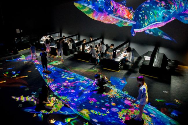 Visitors participate in creating the interactive “Graffiti Nature” at the exhibition held in March in Singapore. (teamLab)