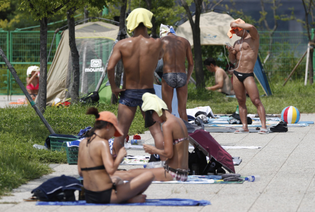 Citizens cool off from the heat at Hanggang River Park in Seoul. (Yonhap)