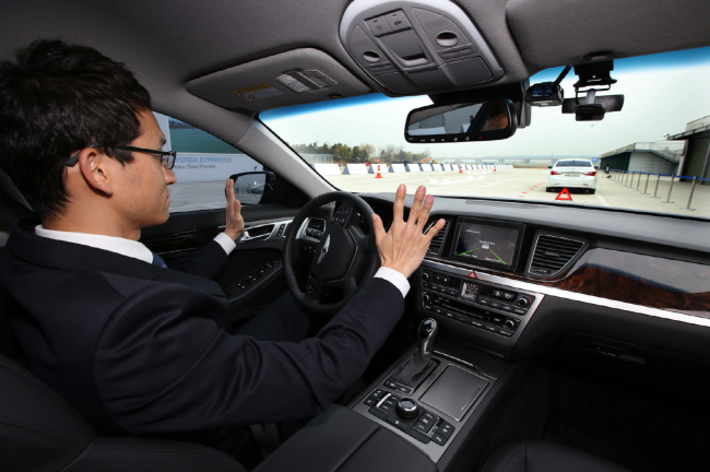 A driver sits behind the wheel of Hyundai Motor`s self-driving Genesis sedan during a road testing event. Hyundai Motor