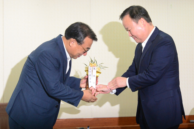 New Saenuri Party leader Rep. Lee Jung-hyun (left) receives a congratulatory orchid from Senior Presidential Secretary for Political Affairs Kim Jae-won at the party’s headquarters on Wednesday. (Yonhap)