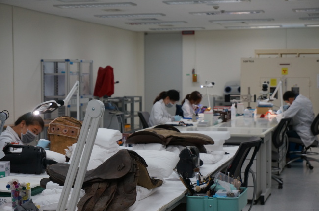 Museum conservators work on artifacts at the conservation science department of the National Palace Museum of Korea. (Lee Woo-young/The Korea Herald)