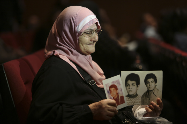 A mother holds up photographs of her children who vanished during the Lebanese civil war from 1975 to 1990, which killed more than 250,000 people. (The International Committee of the Red Cross)