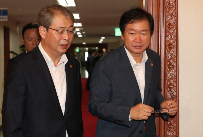Yim Jong-yong (left), chairman of the Financial Services Commission, and Maritime Affairs Minister Kim Young-seok enter a Cabinet meeting hall on Tuesday. (Yonhap)