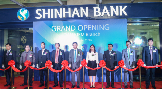 Shinhan Bank Vice President Yoon Seung-wook (left), Korean Ambassador to Hanoi Lee Hyuk (center) and Nguyen Thi Thu Huong (fourth from right), director general for finance at the State Bank of Vietnam, hold a tape-cutting ceremony to mark the launch of the 16th and 17th Shinhan Bank branches in Hanoi on Tuesday. (Shinhan Bank)