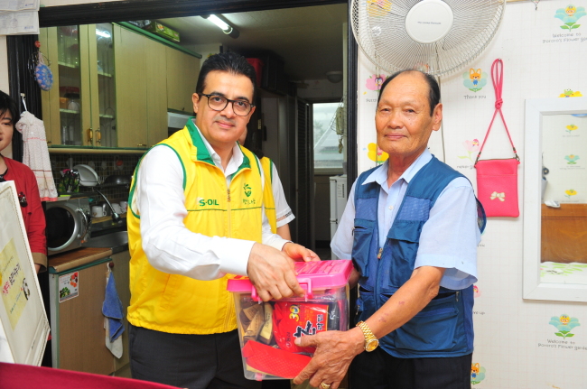 S-Oil‘s new CEO Othman Al-Ghamdi (left) delivers a box filled with songpyeon, groceries and necessities to a low-income household in Seoul on Thursday ahead of the Chuseok holiday next week. (S-Oil)