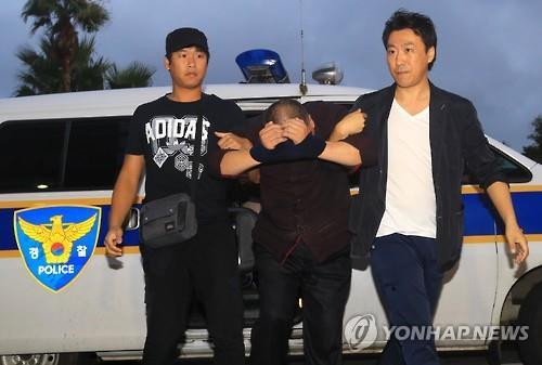 Police officers take a Chinese man, suspected of fatally stabbing a 61-year-old Korean woman who was praying at a local church, to the Jeju Seobu Police Station on the country's resort island of Jeju on Sept. 17. (Yonhap)