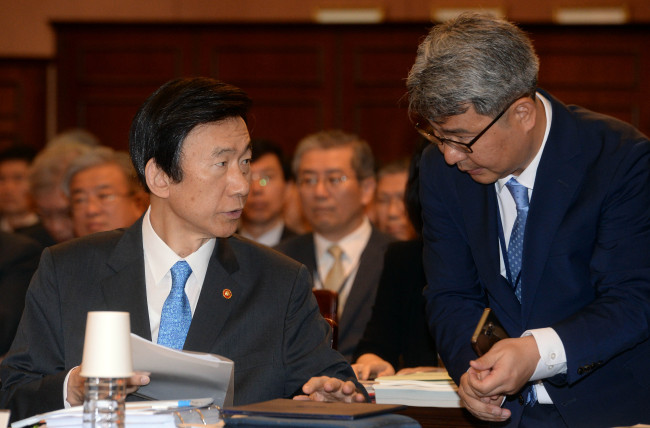 Foreign Minister Yun Byung-se (left) talks with a ministry official during a parliamentary audit Monday at the ministry’s building in central Seoul. (Ahn Hoon/The Korea Herald)