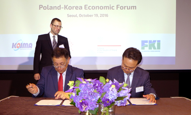 Slawomir Majman, Employers of Poland advisor to the president (left) and Federation of Korean Industries advisor Lee Youn-soo sign a memorandum of understanding at the Poland-Korea Economic Forum on Wednesday. (Joel Lee / The Korea Herald)