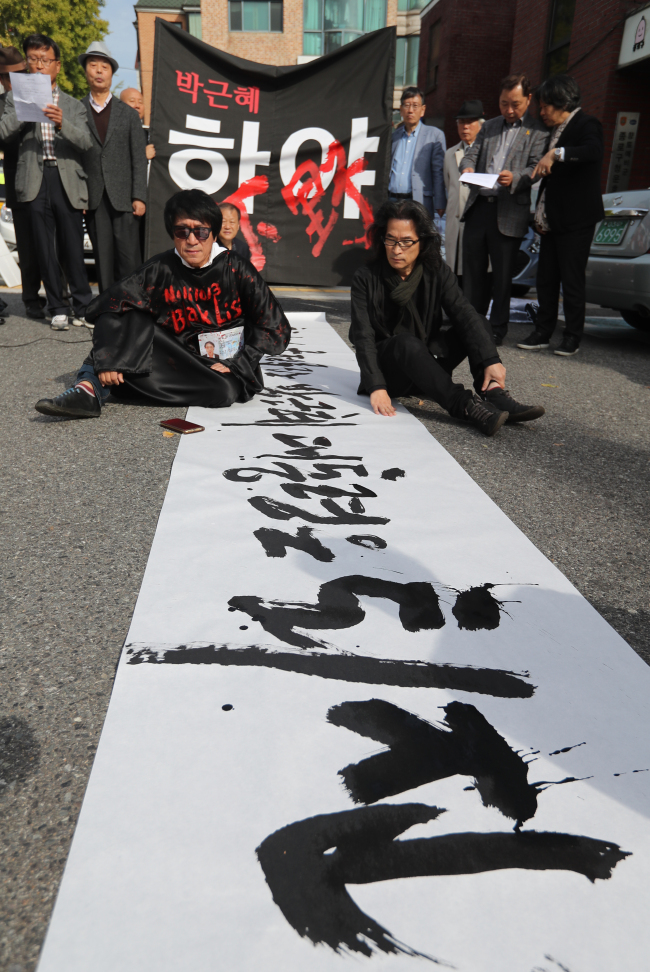 Calligrapher Kang Byeong-in writes “President Park, causing chaos in politics, should resign,” in Korean, as a civil organization announces a declaration denouncing the president in Jongno, central Seoul on Thursday. (Yonhap)