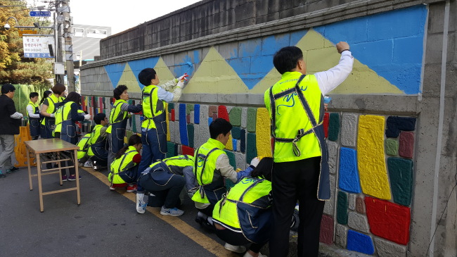 Members of the KDB arts club paint a concrete wall in Munrae-dong, Yeongdeungpo-gu of western Seoul, with vivid colors in order to make the neighborhood look warmer and brighter, on Oct. 22. (KDB)