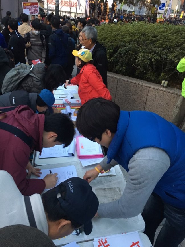 Protestors collect signature demanding President Park Geun-hye step down during a rally held in central Seoul on Saturday. (Yonhap)