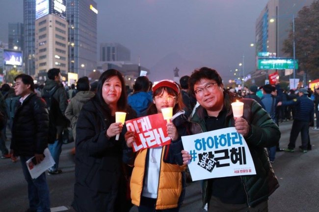Family members hold candles during the anti-Park Geun-hye rally held at Gwanghwamun Square, central Seoul, Saturday. (Son Ji-hyoung/The Korea Herald)