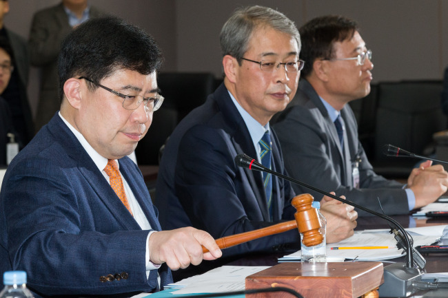 Yoon Chang-hyun, head of the Public Funds Oversight Committee (left) confirms the decision to sell a 29.7 percent government stake in Woori Bank to seven financial institutions at a committee meeting at the Seoul government complex in Gwanghwamun, Seoul, Sunday. (FSC)