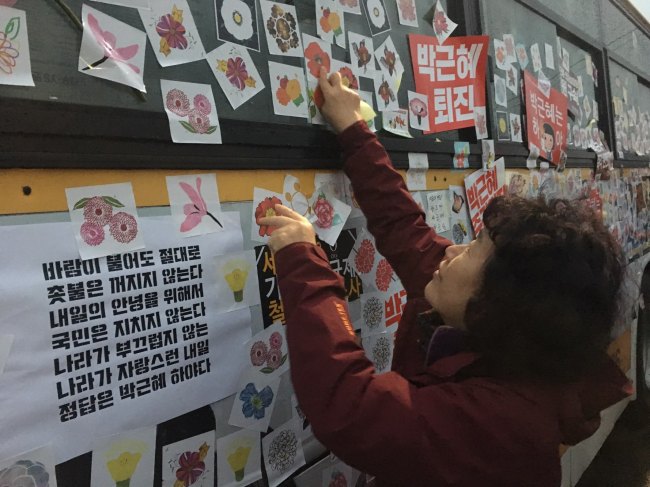 A protestor attaches a flower sticker to a police bus during the anti-Park Guen-hye rally held in central Seoul, Saturday. (Ock Hyun-ju/The Korea Herald)