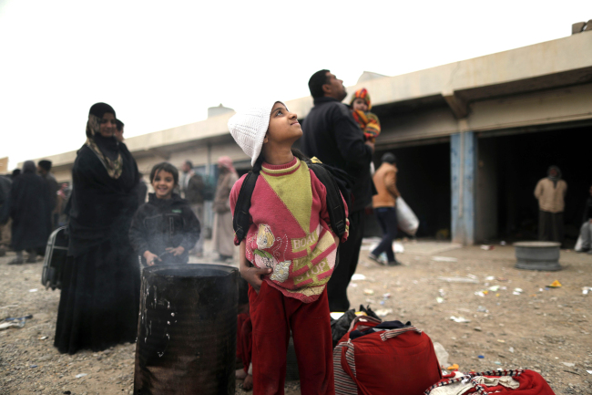 Displaced Iraqi families, who fled Mosul due to the ongoing fighting between Iraqi forces and jihadists of the Islamic State (IS) group, wait before heading to camps housing displaced people, on November 30, 2016 in the town of Bartalla, east of Mosul. (AFP / Yonhap Photo)