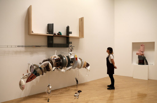 This file photo taken on Sept. 26 shows a woman looking at pieces of artwork forming an installation by artist Helen Marten at Tate Britain in London. (AFP-Yonhap)