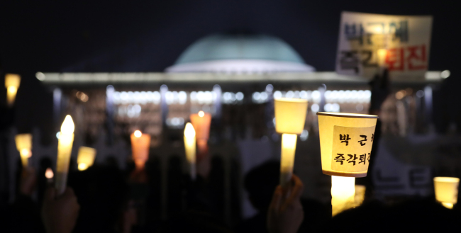 Protesters hold up candles outside the National Assembly in Seoul on Tuesday, as they continue their daily rally demanding the impeachment of President Park Geun-hye. (Yonhap)