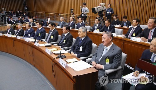 South Korea's top business moguls shake hands with lawmakers while attending the National Assembly hearing Tuesday. (Yonhap)