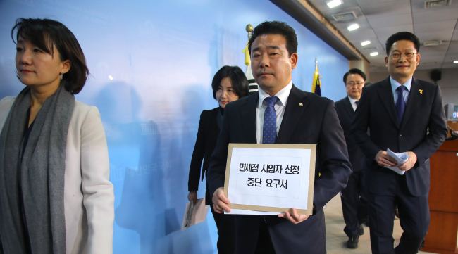 Opposition and independent lawmakers exit after a press conference calling for a stop to the evaluation for new duty-free licenses Tuesday. (Yonhap)