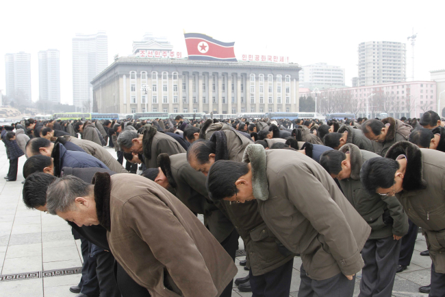 People bow to portraits of the late leaders, Kim Il-sung and Kim Jong-il, at the Kim Il-sung Square in Pyongyang, North Korea, Saturday, to mark the fifth anniversary of Kim Jong-il's death. (AP Photo/Kim Kwang Hyon)