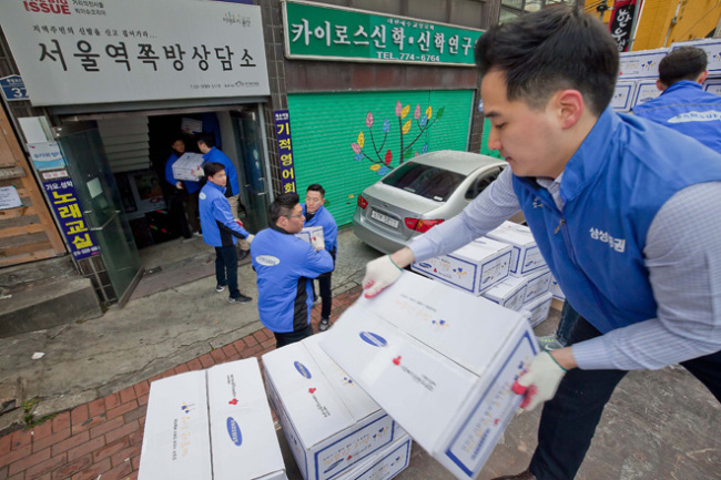 Samsung employees deliver necessities to elderly people living along near Seoul Station on Dec. 7. Samsung Group