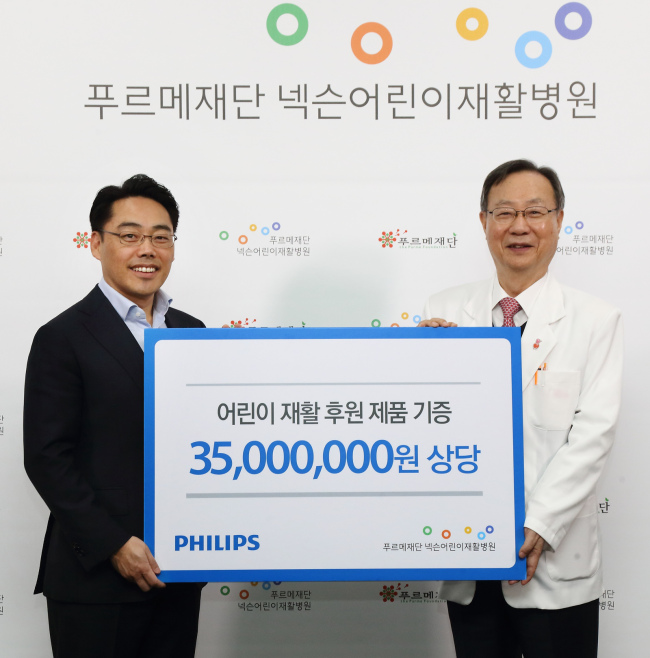 General Manager of Philips Korea’s Personal Health business division Peter Kwak (left) presents a check for 35 million won ($29,300) worth of dental and household goods to Purme Foundation Nexon Children’s Rehabilitation Hospital President Yim Yoon-myung. (Philips Korea)