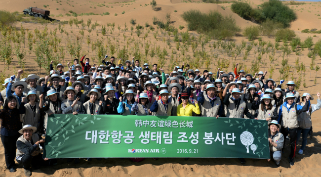 Korean Air employees and college students at Kubuchi Desert in China pose at an annual tree-planting event in September. (Korean Air)