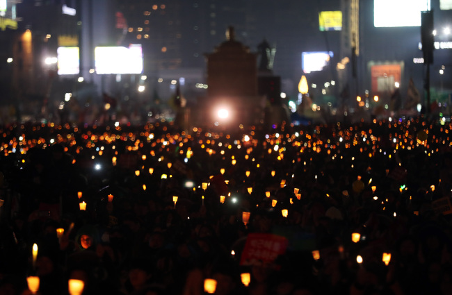 Protestors hold candles at the 10th Saturday night rally against President Park Geun-hye, held on the last day of 2016 at Gwanghwamun Square in central Seoul. (Yonhap)