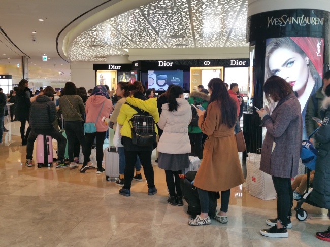 Shoppers stand in line in the cosmetics section of Lotte Duty Free‘s World Tower branch in southern Seoul, Thursday morning. (Won Ho-jung/The Korea Herald)