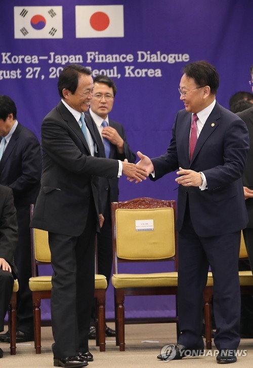 South Korea`s Finance Minister Yoo Il-ho (R) shakes hands with his Japanese counterpart Taro Aso at the Korea-Japan finance ministers meeting in Seoul on Aug. 27, 2016. (Yonhap file photo)