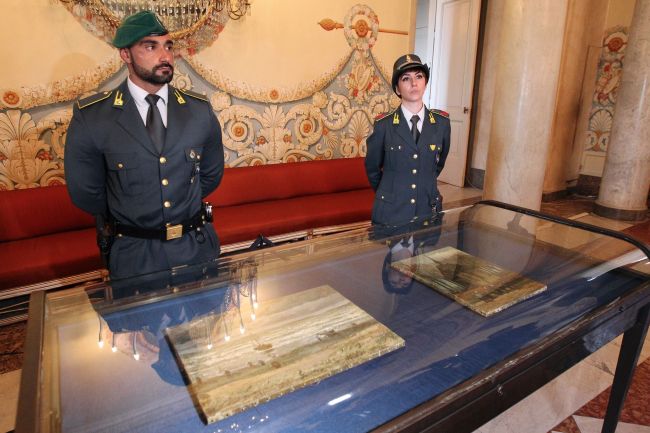 Two Italian policemen of the Guardia di Finanza (Financial Police) stand guard by the two recently recovered stolen paintings by late Dutch artist Vincent Van Gogh -- “Congregation Leaving the Reformed Church in Nuenen” and “The Beach At Scheveningen During A Storm” -- displayed at the Capodimonte Museum in Naples on Monday for an exhibition before their return at the Van Gogh Museum. AFP-Yonhap