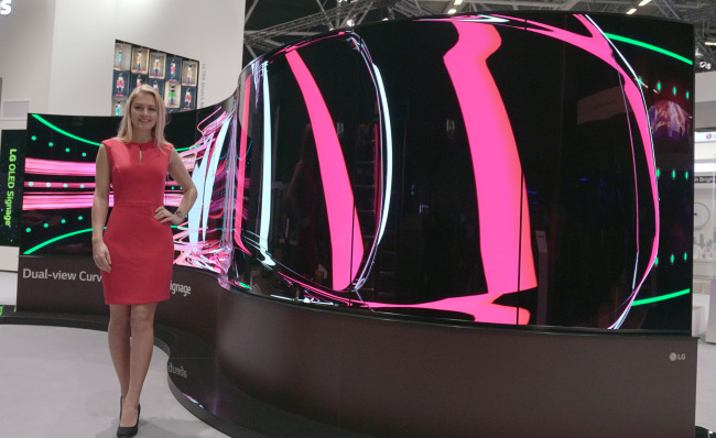 An employee introduces LG’s two-side OLED Signage display panel, which can be folded in a wave shape, at the ISE 2017 convention in Amsterdam, the Netherlands, Tuesday. (LG Electronics)