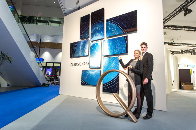 Employees show Samsung’s QLED Signage display panels hung on the wall at the ISE 2017 convention in Amsterdam, the Netherlands, Tuesday. (Samsung Electronics)