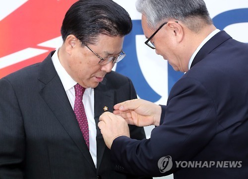 In Myung-jin (R), the interim head of the Liberty Korea Party, clips a lawmaker lapel badge to Rep. Bak Maeng-woo at the party's headquarters in Seoul on Feb. 14, 2017. (Yonhap)