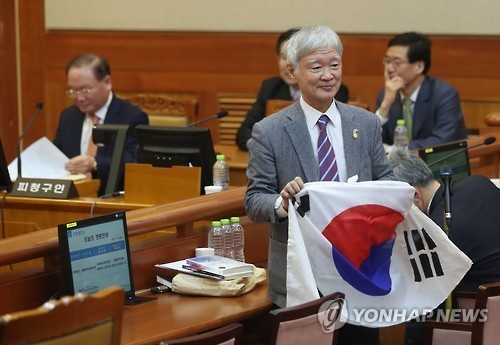 Seo Seog-goo holds up the Korean flag inside the main courtroom of the Constitutional Court in Seoul on Feb. 14, 2017. (Yonhap)