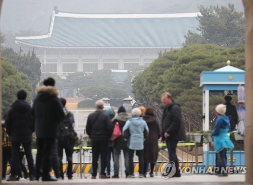 Foreign tourists look on from the photo zone of the fine dust-blanketed presidential office Cheong Wa Dae in Seoul on Dec. 5, 2016. (Yonhap)