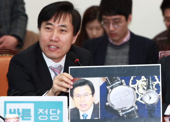 Rep. Ha Tae-keung of the Bareun Party shows a picture of a souvenir watch inscribed with “Acting President Hwang Kyo-ahn” during a party meeting at the National Assembly in Yeouido, Seoul, Friday. (Yonhap)