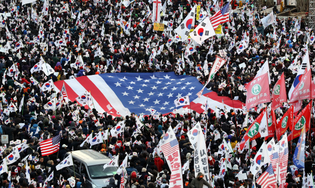Conservative civic groups march with Korean flags and a giant American flag during a rally against impeachment of President Park Geun-hye at Seoul Square, central Seoul on Saturday. (Yonhap)