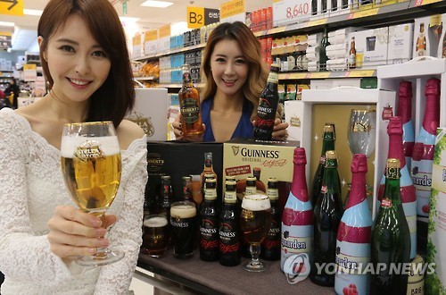 Models pose with various imported beer brands at a supermarket in Seoul in this file photo released by E-Mart on Jan. 2, 2017. (Yonhap)