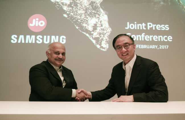 Kim Young-ky (right), the president and head of networks business at Samsung Electronics, shakes hands with Jyotindra Thacker, president of Reliance Jio, at a joint press conference in Barcelona, Spain, Tuesday. (Samsung Electronics)