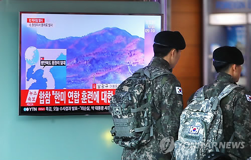 South Korean soldiers walk past a TV broadcasting North Korea's launch of several ballistic missiles into the East Sea at Seoul Station on March 6, 2017. The unidentified projectiles were launched from an area near the North's Dongchang-ri long-range missile site at 7:36 a.m. and flew about 1,000 kilometers before splashing into the East Sea, Seoul's Joint Chiefs of Staff said. (Yonhap)