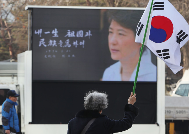 A pro-Park protester waves the national flag during a rally in central Seoul on Saturday. (Yonhap)