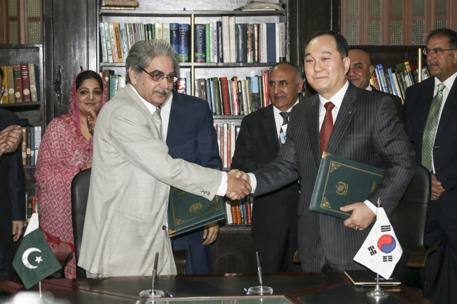 Chang Young-hoon (right), executive director of the Export-Import Bank of Korea, shakes hands with Tariq Mahmood Pasha, secretary of the economic affairs division of Pakistan, after signing on a $76 million EDCF agreement in Islamabad, Pakistan, Tuesday. Export-Import Bank of Korea