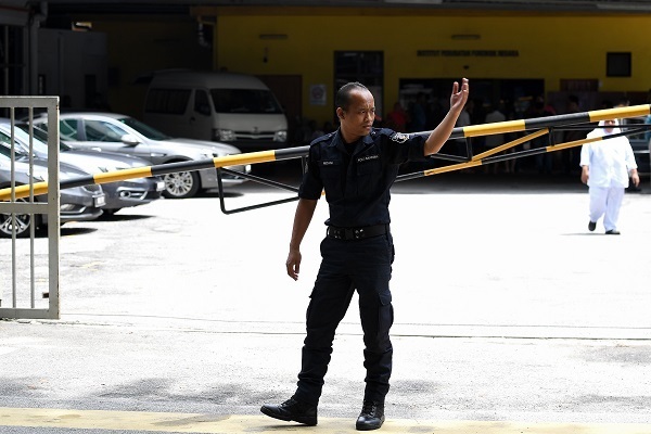 A Malaysian policeman controls traffic outside the forensics wing of Hospital Kuala Lumpur, where the body of Kim Jong-nam, the half brother of North Korea’s leader Kim Jong-un, lies in Kuala Lumpur on Monday. (AFP-Yonhap)