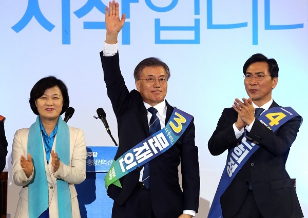 Presidential front-runner Moon Jae-in (C) waves to his supporters after securing his second victory in a party primary held in Daejeon, located some 160 kilometers south of Seoul, on March 29, 2017. His closest rival and South Chungcheong Province Gov. An Hee-jung (R) came in second. (Yonhap)