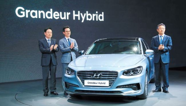 Hyundai Motor Executive Vice Presidents Hwang Seung-ho and Lee Kwang-guk and Vice Chairman Yang Woong-chul, pose for photo with a hybrid version of the Grandeur unveiled in a world premiere on the eve of the 11th Seoul Motor Show on Thursday. (Yonhap)