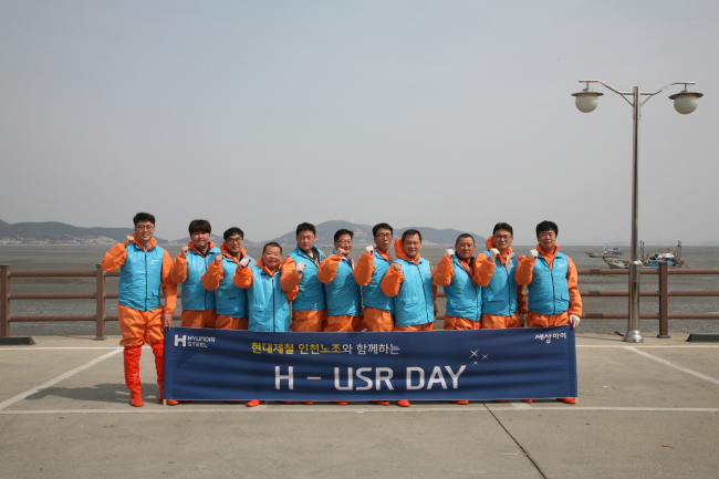 The labor union of Hyundai Steel’s Incheon factory poses during a volunteer program to eliminate cordgrass at Dongmak beach in Incheon. (Hyundai Steel)